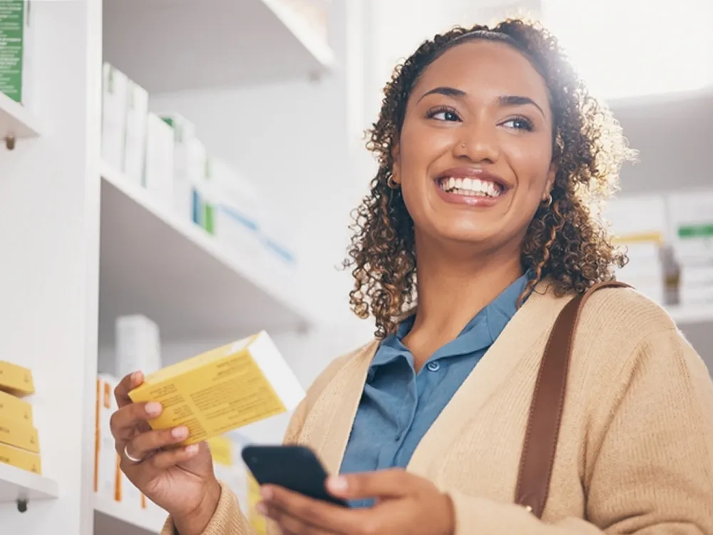 Mulher sorrindo segurando uma caixa de medicamentos